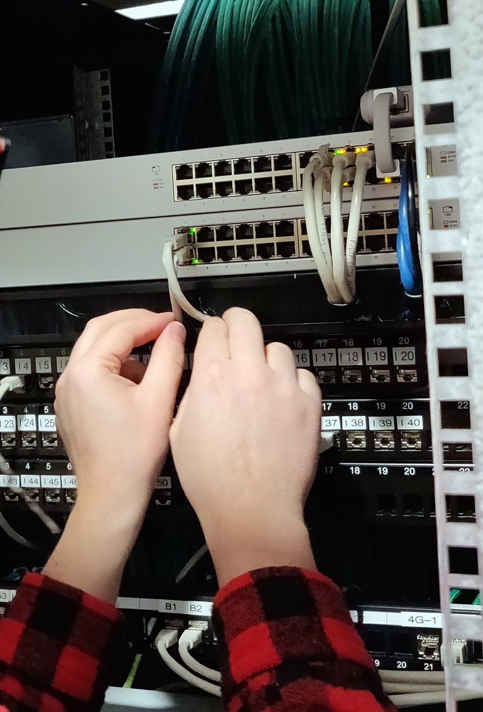 Les mains d’un technicien branchant un cordon sur un panneau de brassage.