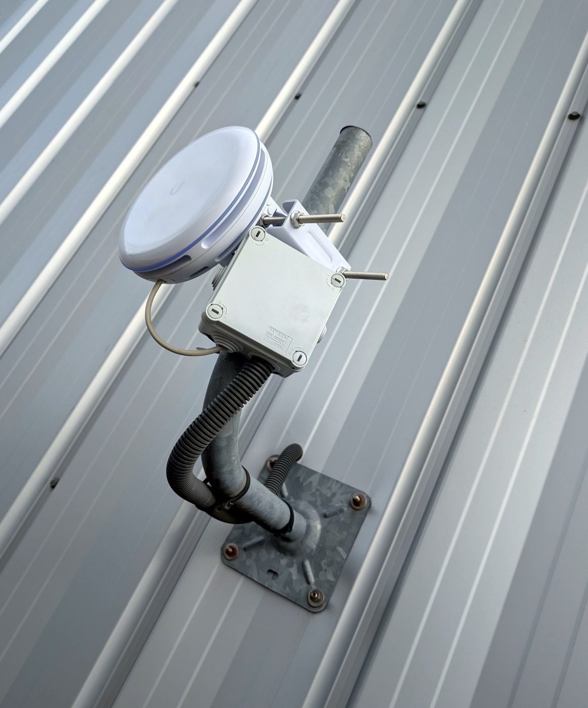 Une borne Wi-Fi extérieure montée sur potence galvanisée, avec boîtier de dérivation et gaines.