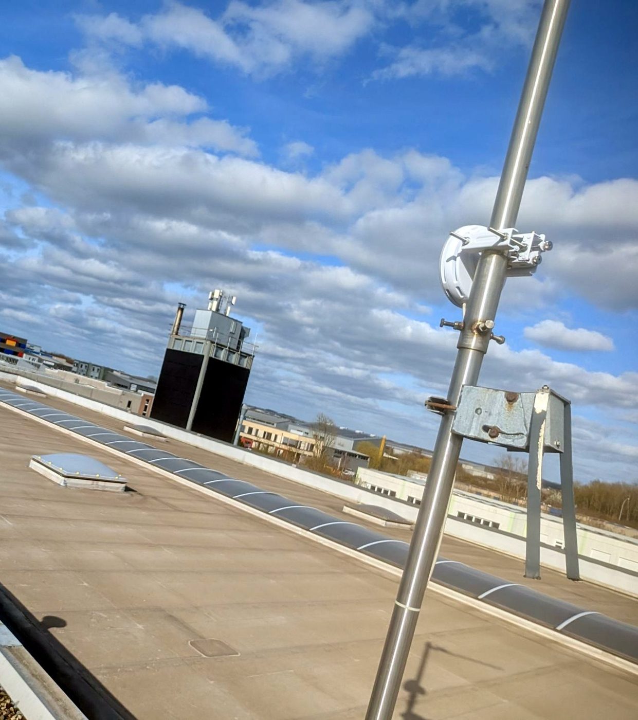 Un mât d’antenne installé en toiture d’un bâtiment d’activité, assurant une liaison sans fil entre sites.
