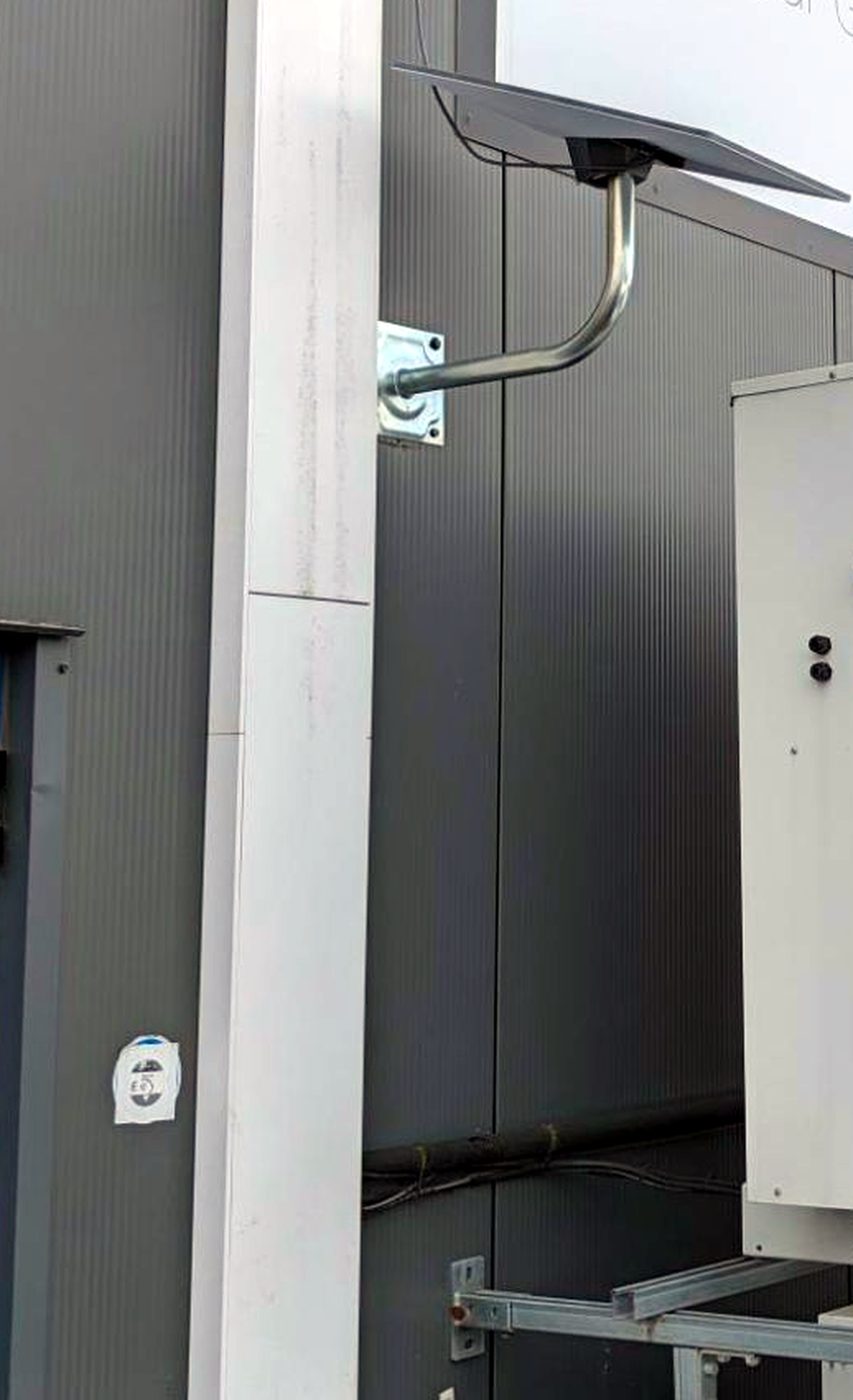 Une parabole Starlink installée sur potence, fixée au bardage d’un bâtiment d’activité.